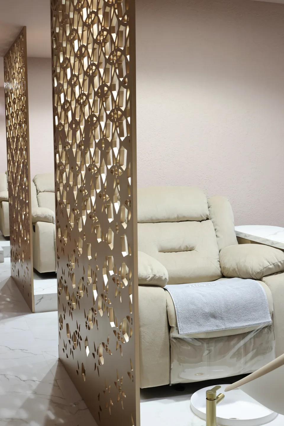 Cream VIP chairs framed by bronze privacy screens upstairs at Beauty Airways