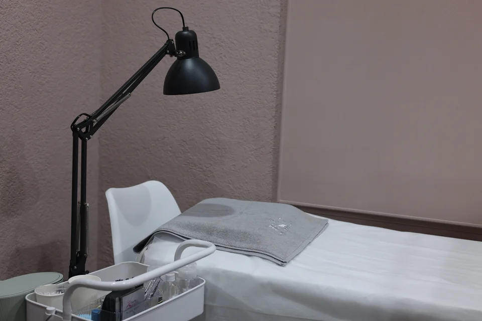 Prepared lash room with a Beauty Airways towel, a treatment bed and black task lamp